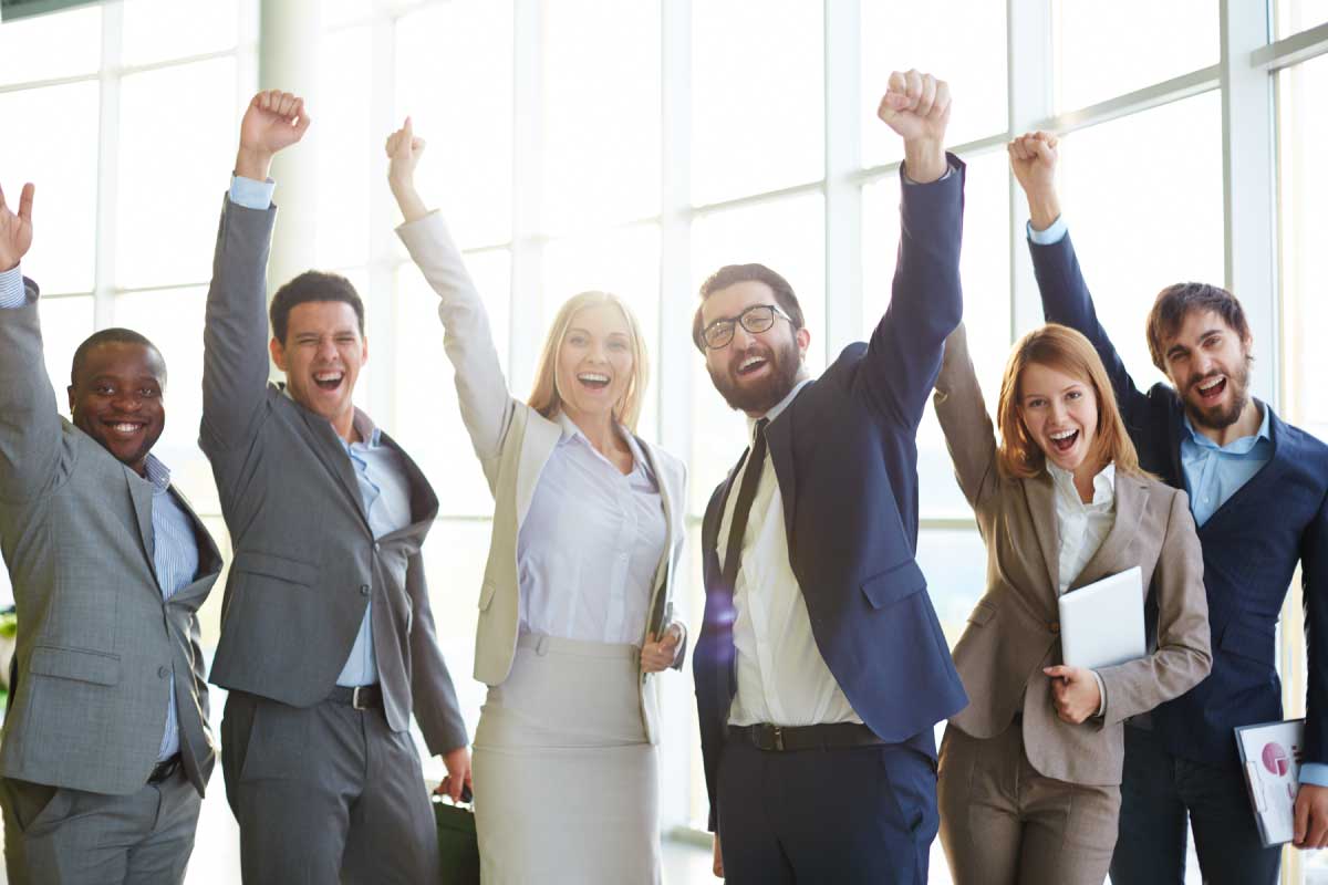 Grupo de personas de negocios con sus manos levantadas, celebrando un triunfo.