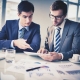 Dos hombres de negocios analizando información en una tableta electrónica.
