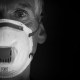 Fotografía a blanco y negro de la cara de un hombre usando una mascarilla de respiración con filtro.