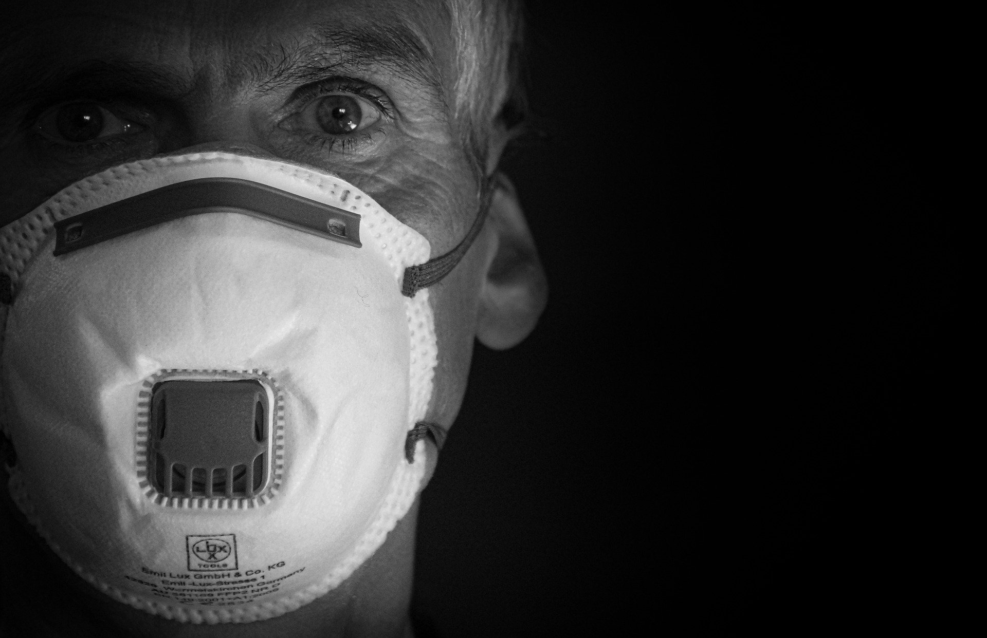 Fotografía a blanco y negro de la cara de un hombre usando una mascarilla de respiración con filtro.