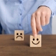 Persona escogiendo un cubo que tiene un emoji de una cara feliz sobre el que tiene la cara triste