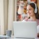 Mujer joven al frente de un computador y con audífonos