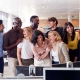 Grupo de compañeros de trabajo en una oficina, sonriendo alegremente.