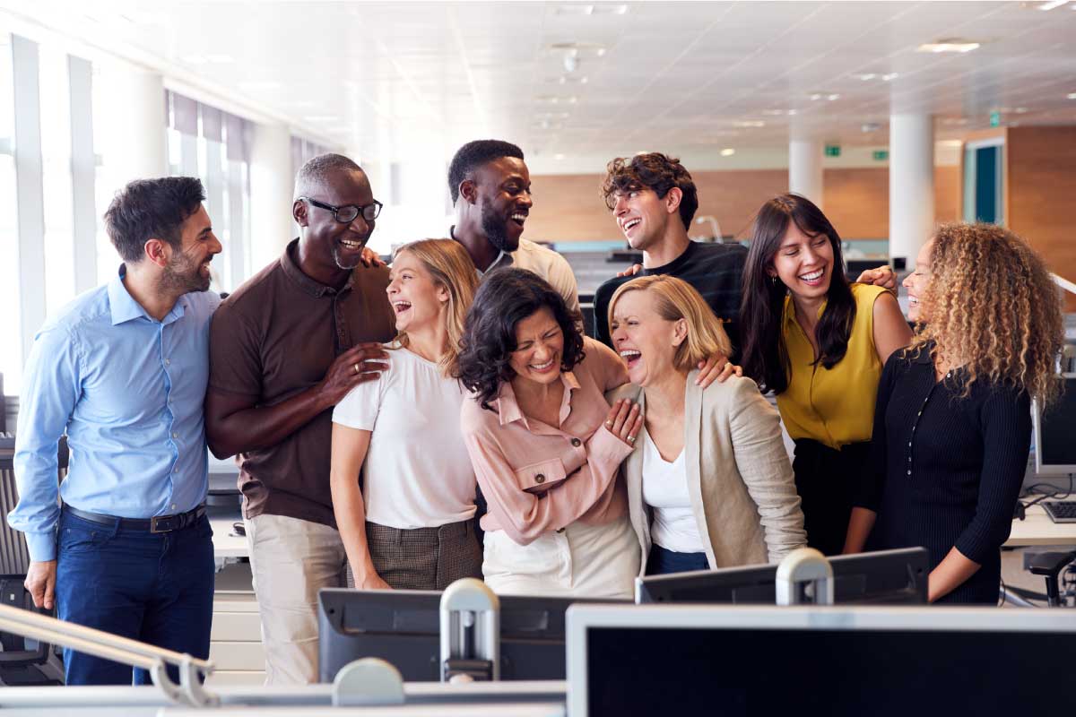 Grupo de compañeros de trabajo en una oficina, sonriendo alegremente.