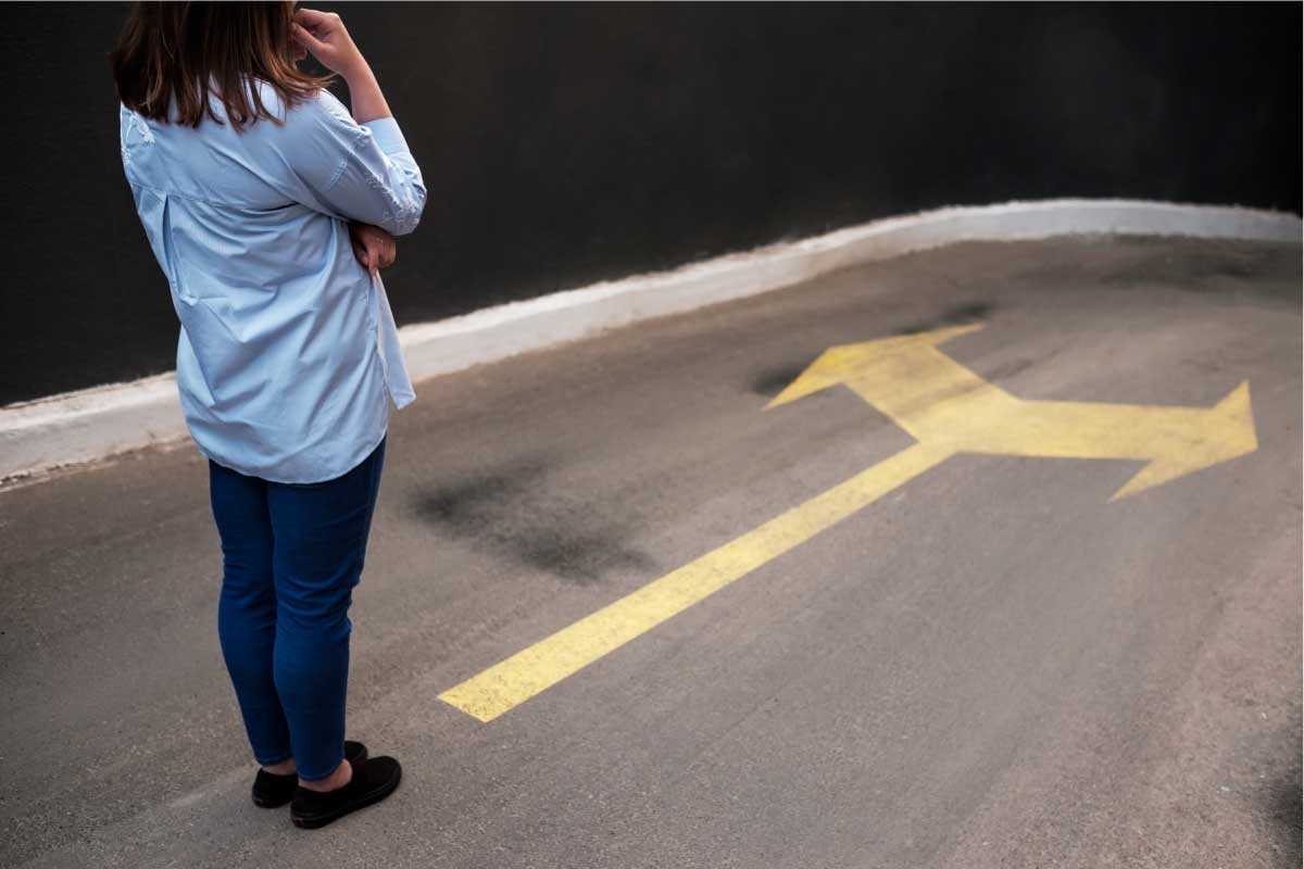 Mujer parada en la calle con una señal de girar a la derecha o izquierda