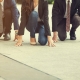 Tres ejecutivos en la calle, agachados con un rodilla y las manos en el suelo a punto de comenzar una carrera