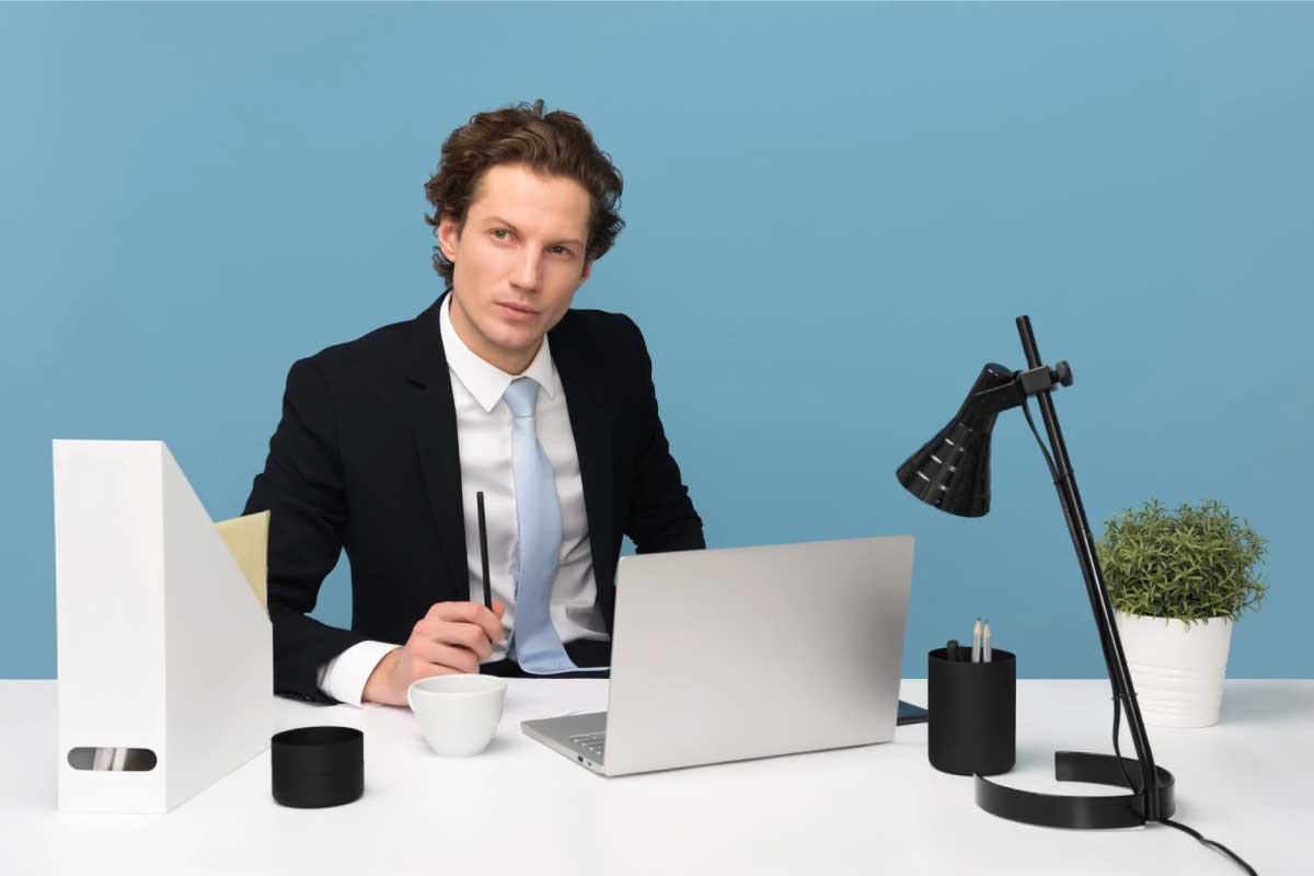 Hombre joven de negocios sentado al frente de un computador.