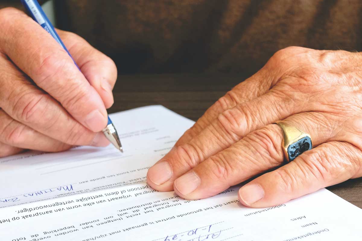 Acercamiento de las manos de un hombre adulto, firmando papeles
