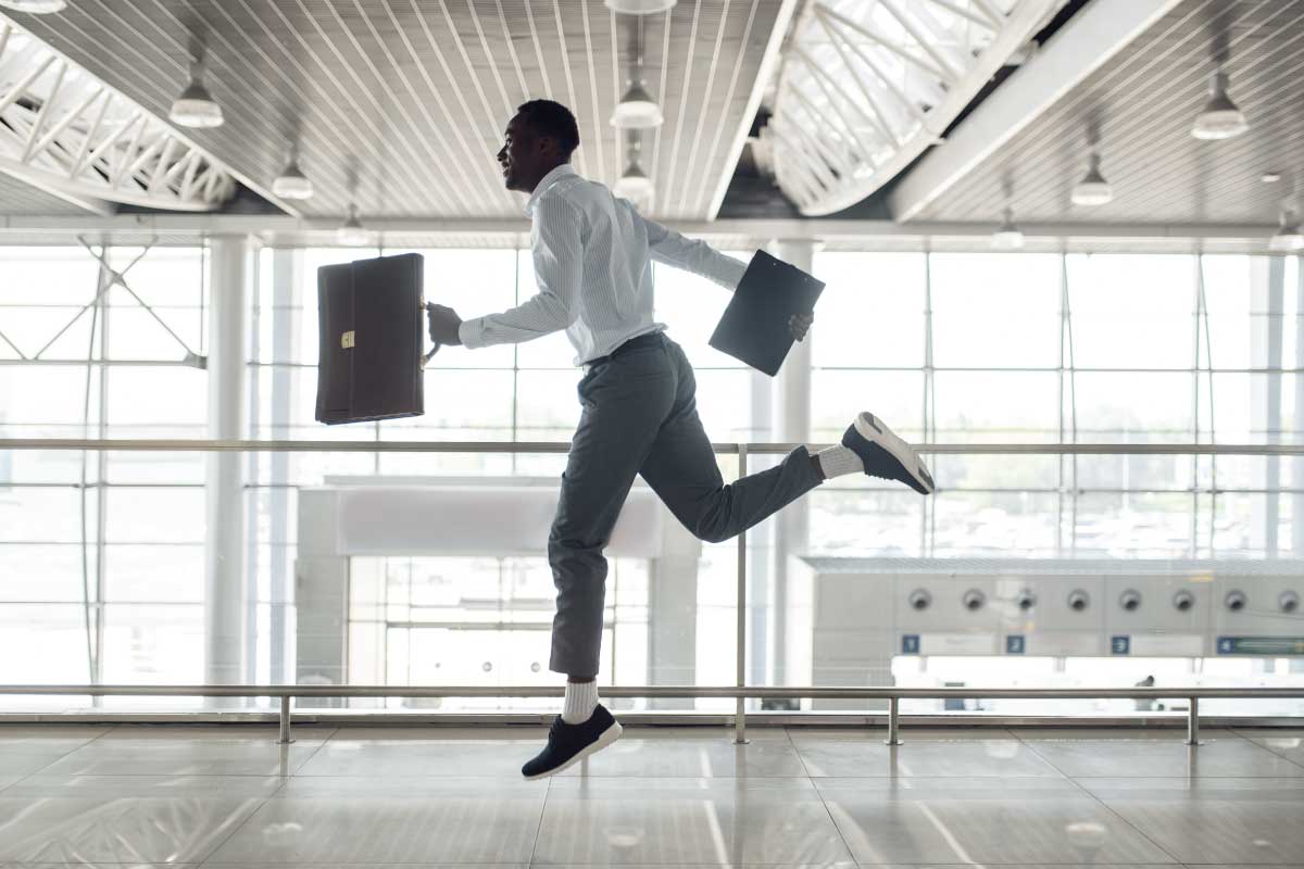 Hombre ejecutivo saltando con sus brazos abiertos sosteniendo un portafolio en una mano y una libreta en la otra.
