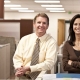 Dos ejecutivos en una oficina sonriendo a la cámara.