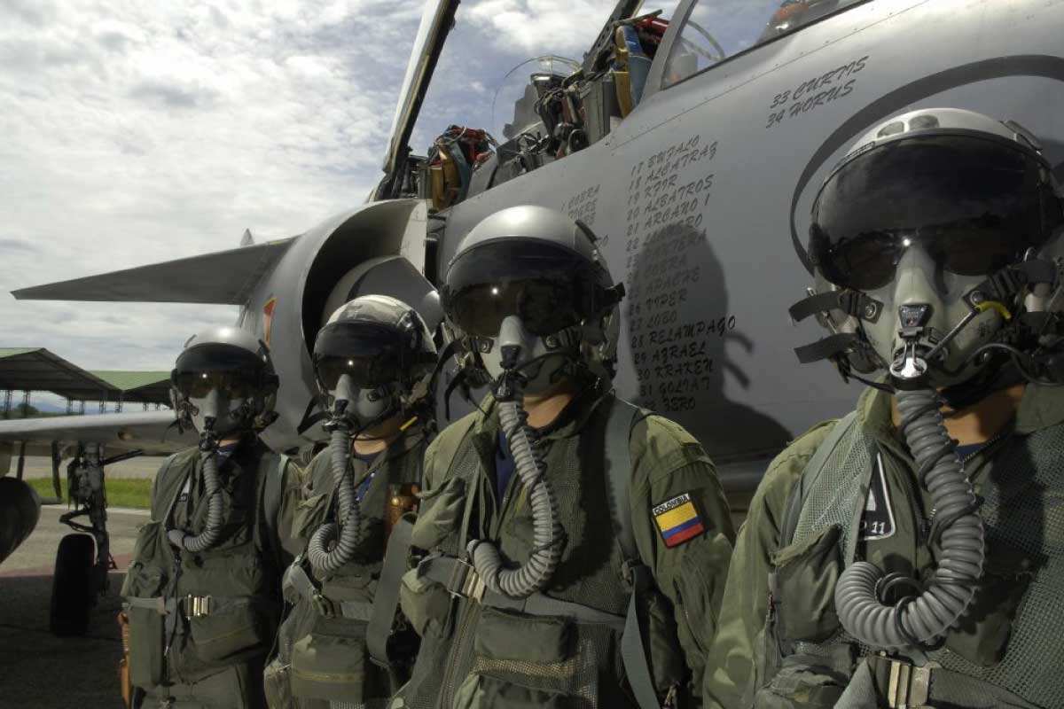 Grupo de oficiales con uniforme y casco de la fuerza aérea, parados al frente de un avión militar.