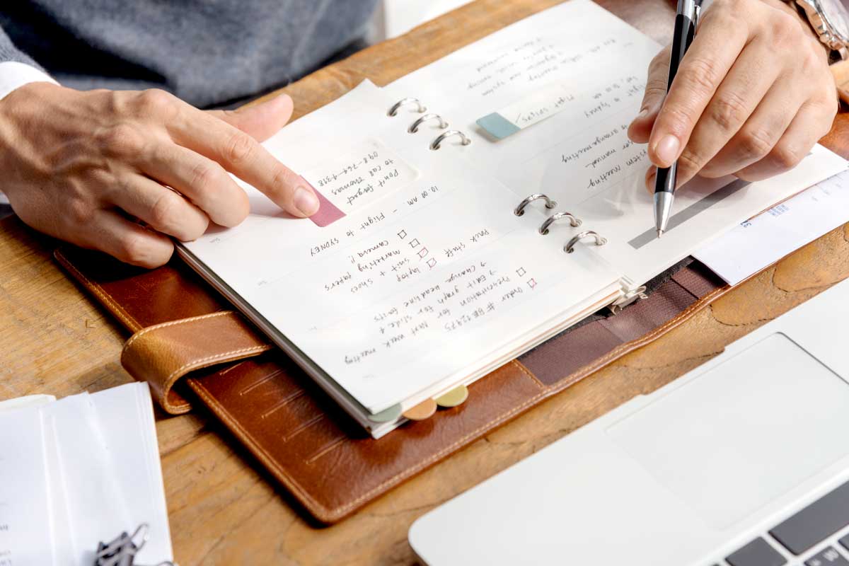 Hombre escribiendo en un cuaderno, revisando sus notas