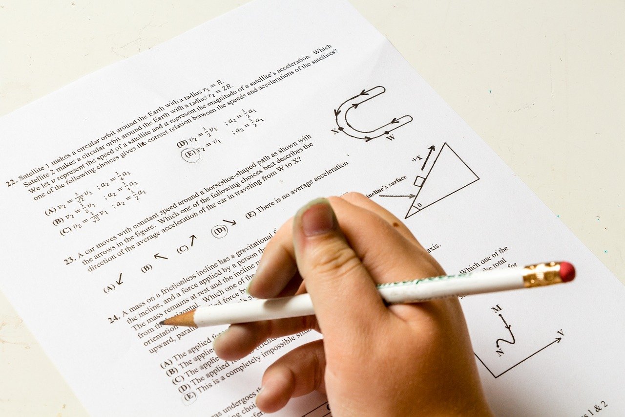 Acercamiento de la mano de un estudiante respondiendo un examen de matemáticas.