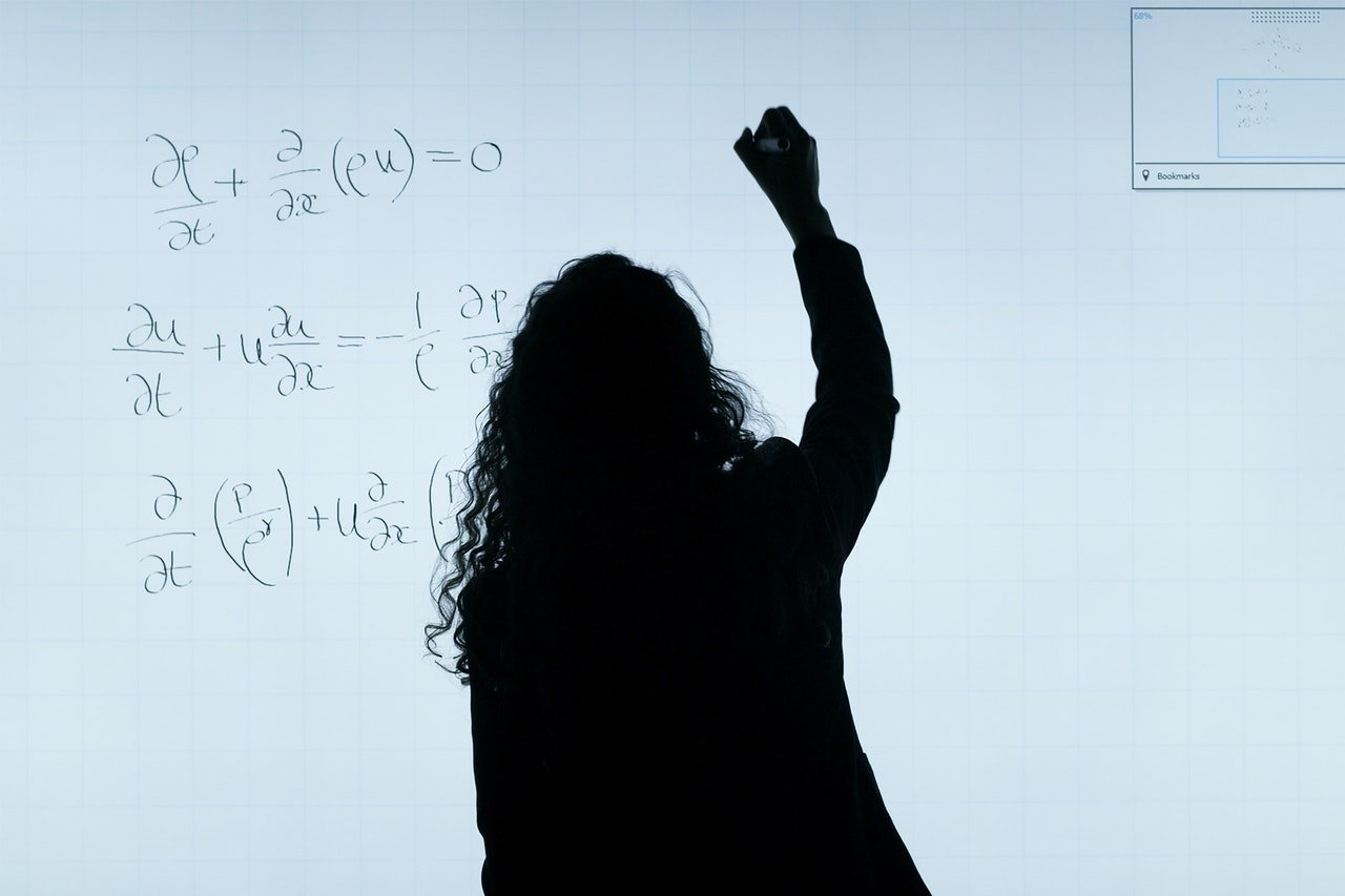 Mujer escribiendo una ecuación en un tablero