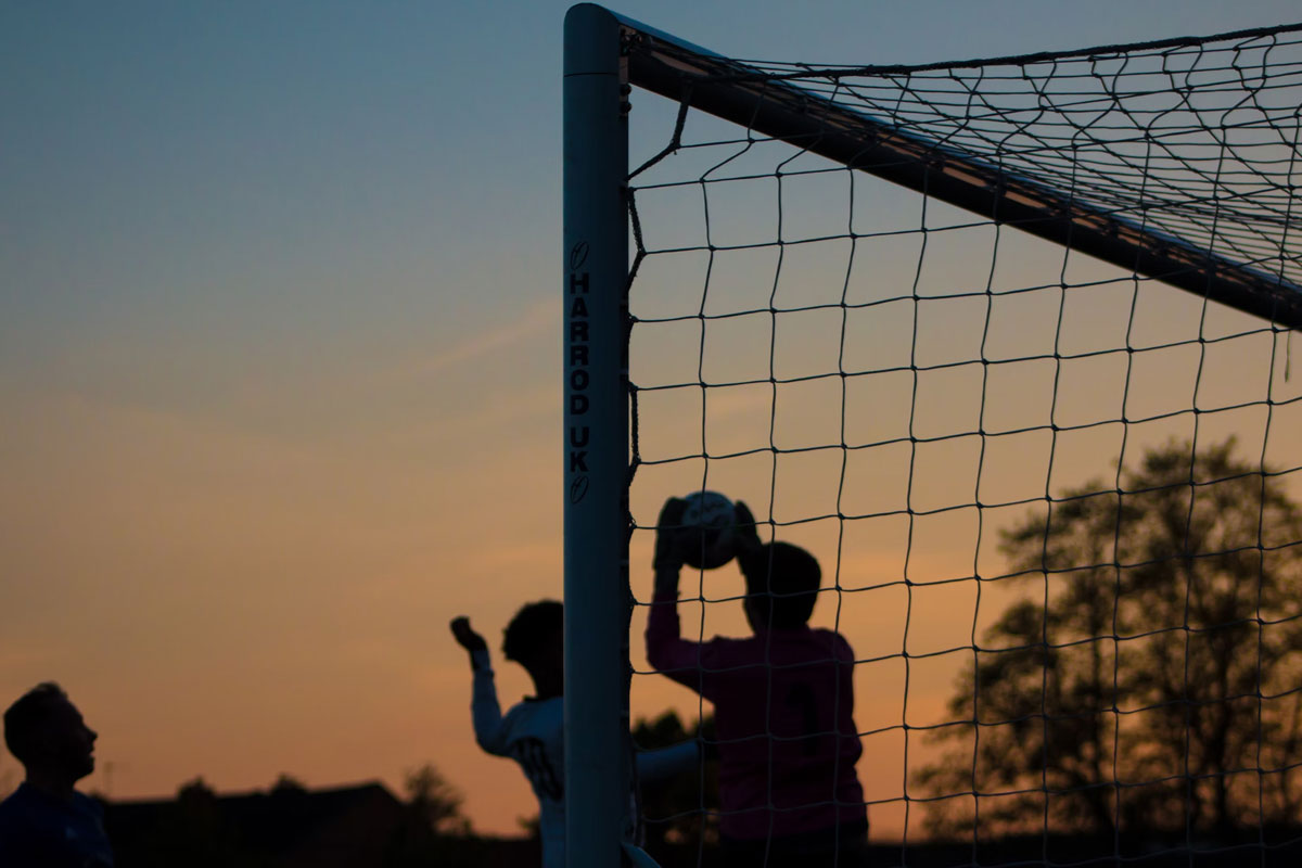 Grupo de personas jugando fútbol al atardecer.